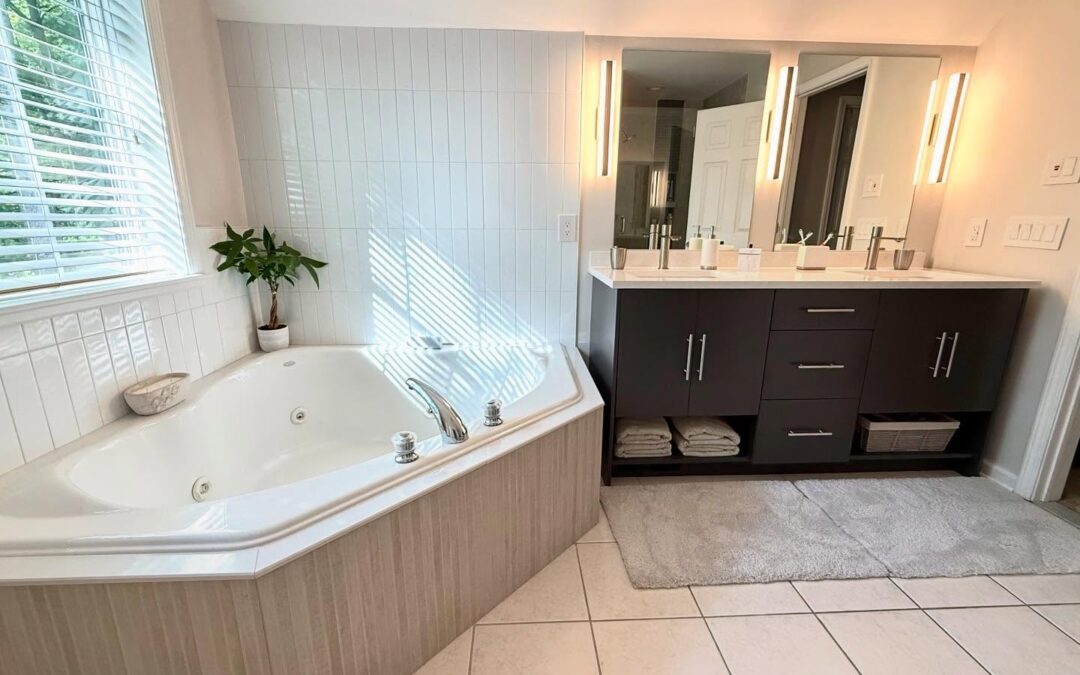 Elegant bathroom remodel with modern fixtures, quartz vanity, jacuzzi tub, and stylish tile work, designed by Kitchen & Bath World.